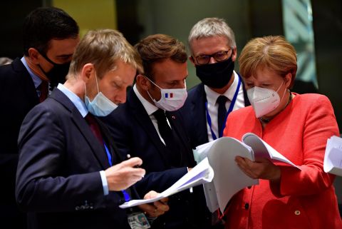 Merkel and other world leaders look over documents during a European Union summit in Brussels, Belgium, in July 2020. Leaders agreed to create a <a href=