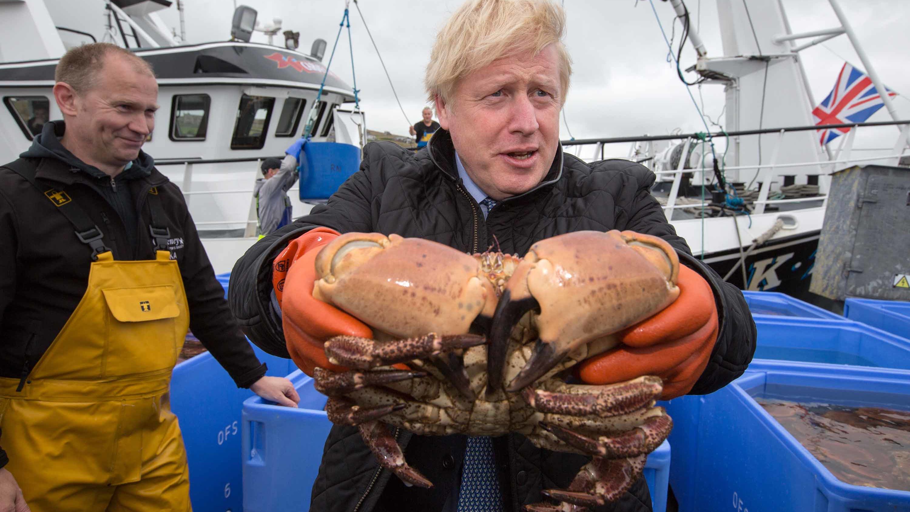 Johnson holds a crab in Stromness Harbour during a visit to Scotland in July 2020.