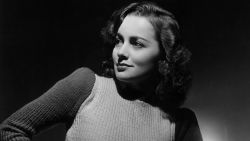 circa 1935:  Studio portrait of British-born actor Olivia de Havilland sitting on a stool and looking over her shoulder as she rests her hand on her hip.  De Havilland is wearing a long wool skirt and a knit sweater.  (Photo by Hulton Archive/Getty Images)