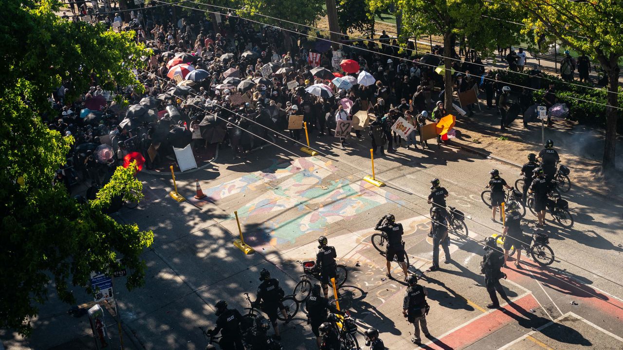Police push demonstrators back atop a Black Lives Matter street mural in the area formerly known as CHOP during protests in Seattle on Saturday, July 25.
