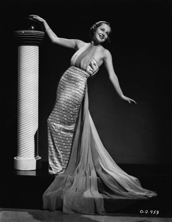 De Havilland strikes a pose in a gown with a flowing train (circa 1936).