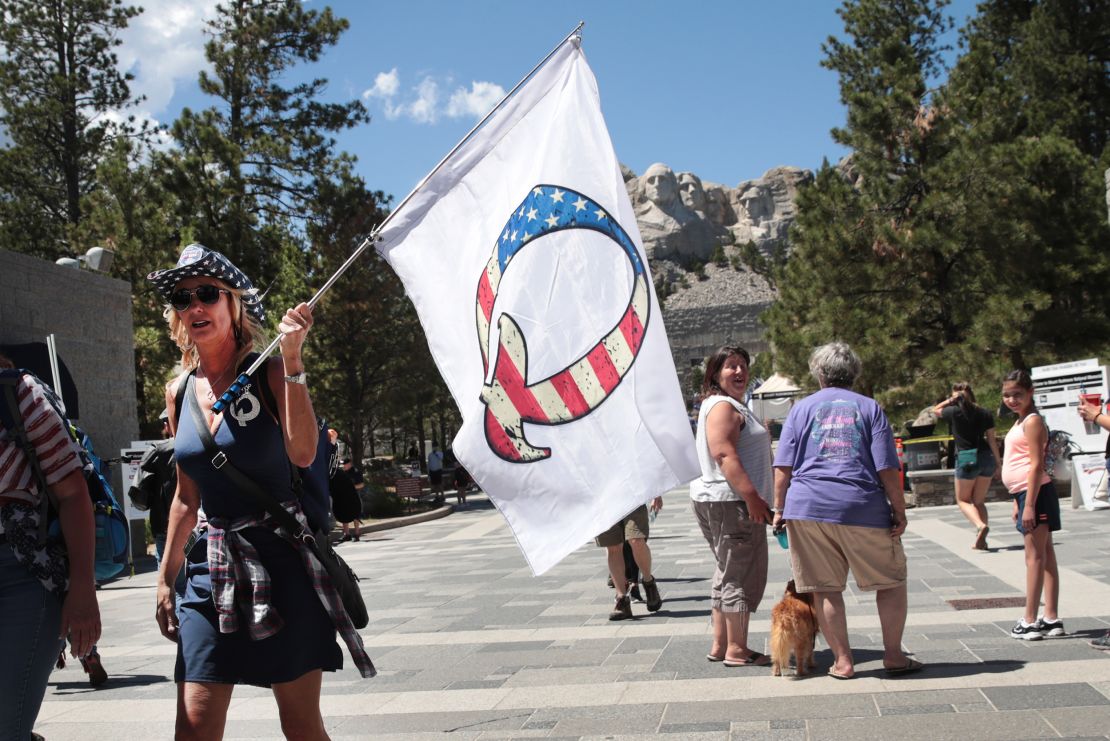A Donald Trump supporter holding a QAnon flag visits Mount Rushmore National Monument in the US state of South Dakota on July 01, 2020.