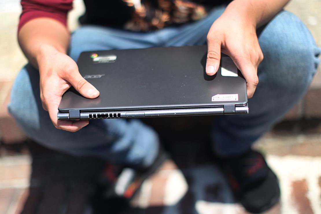 Jose Escobar holds his laptop in Brighton, Massachusetts, on May 21, 2020. Escobar told The Boston Globe the laptop given to him by his school for online learning did not work.