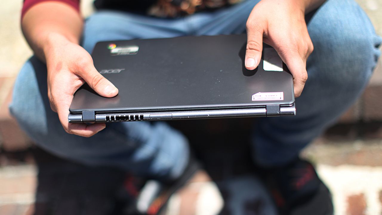 Jose Escobar holds his laptop in Brighton, Massachusetts, on May 21, 2020. Escobar told The Boston Globe the laptop given to him by his school for online learning did not work. 