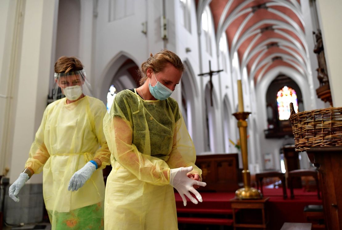 Nurses put on protective gear and gloves before taking a nasal swab test for the novel coronavirus at a temporary testing center at a church in Antwerp, Belgium, on Monday.