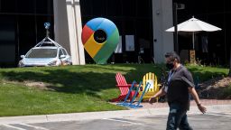 A person wearing a protective mask walks past a building at the Google campus in Mountain View, California, U.S., on Monday, July 27, 2020. Alphabet Inc.'s Google will let employees work from home until July 2021, once again pushing back the re-opening of its offices as the coronavirus continues to rage in many parts of the U.S. Photographer: David Paul Morris/Bloomberg via Getty Images