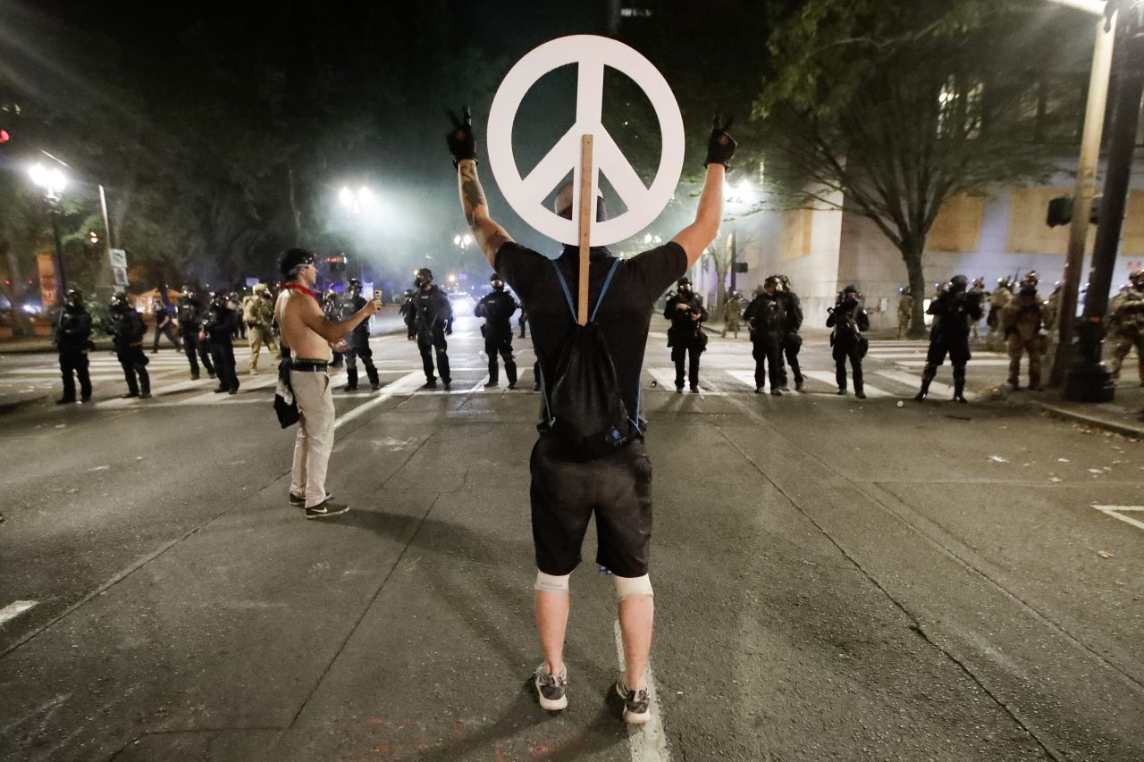 A demonstrator flashes peace signs at federal officers on July 29.