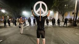 A demonstrator flashes a peace sign at federal officers during a Black Lives Matter protest at the Mark O. Hatfield United States Courthouse Wednesday, July 29, 2020, in Portland, Ore. (AP Photo/Marcio Jose Sanchez)