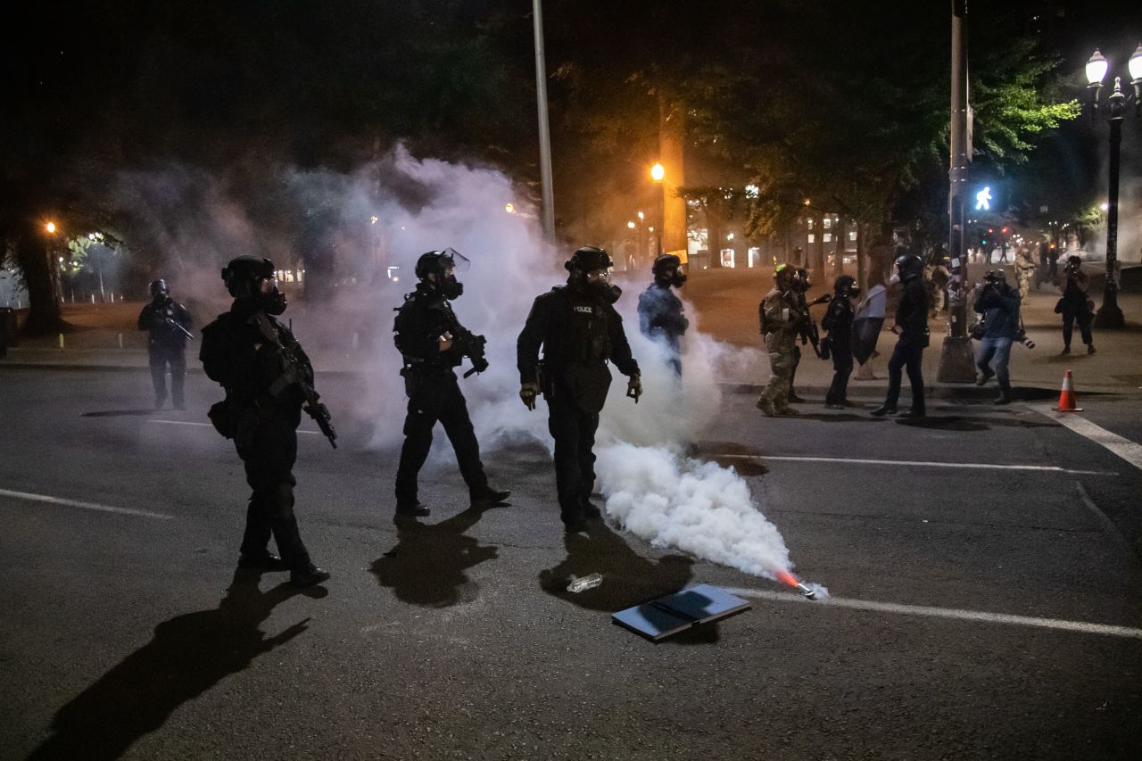 Police and federal officers walk through the street on July 28, deploying tear gas and other methods to disperse protesters.