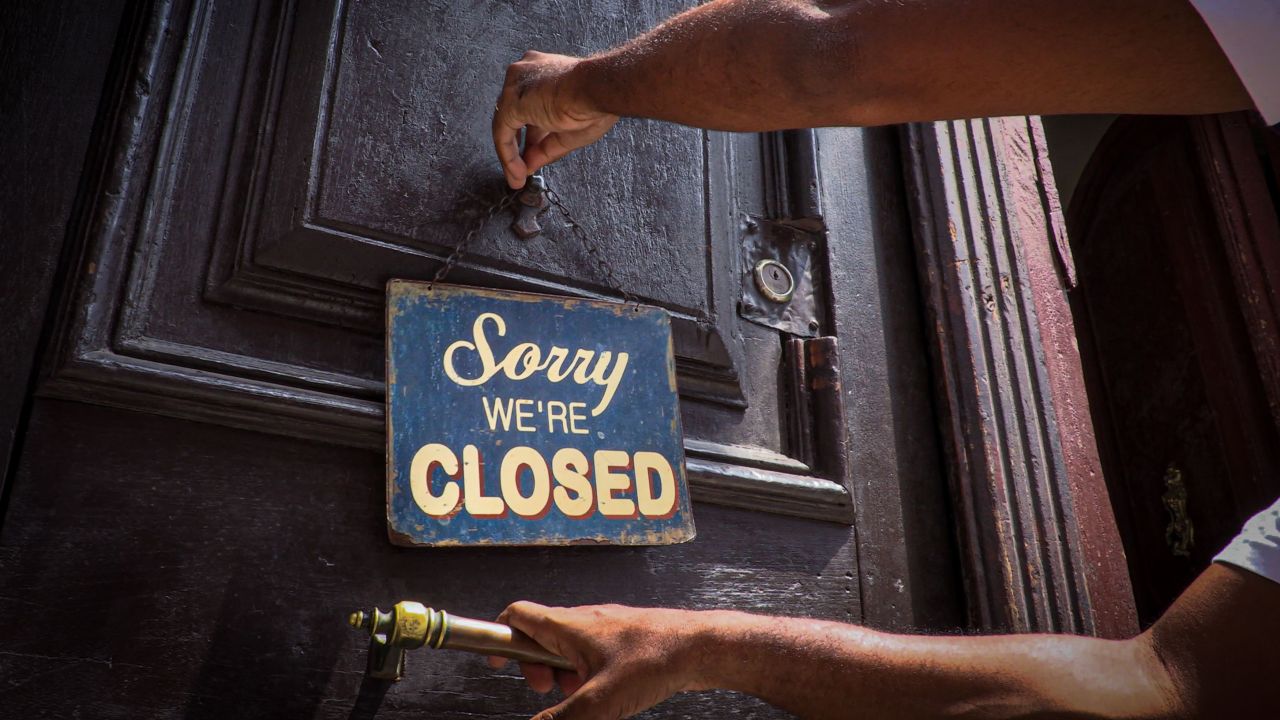 TOPSHOT - An employee hangs a sign outside the door of Nelson's Cafe in Havana on March 16, 2020, amid the new coronavirus pandemic. - With American convertible cars in their garages and closed bars and restaurants, Havana is a dead city. The private sector in Cuba is suffering the lack of tourists as a consequence of the lockdown imposed as a measure against the spread of the new coronavirus. (Photo by ADALBERTO ROQUE / AFP) (Photo by ADALBERTO ROQUE/AFP via Getty Images)