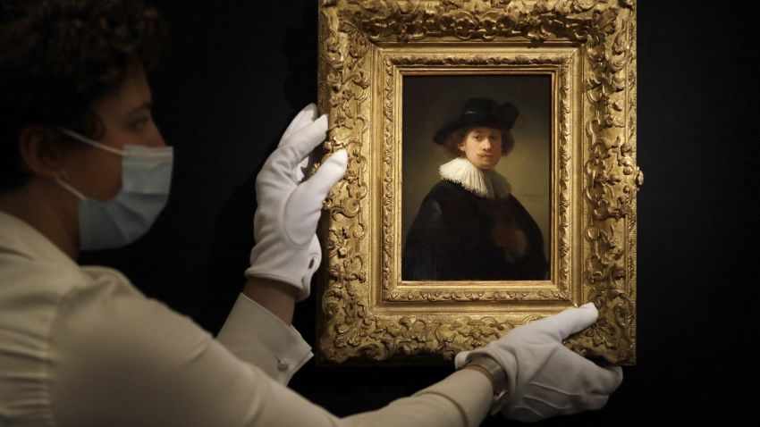 FILE - In this Thursday, July 23, 2020 file photo, a Sotheby's employee adjusts a painting by Rembrandt, entitled 'Self-portrait, wearing a ruff and black hat' at Sotheby's auction rooms in London. The auction house Sotheby's is holding an online sale featuring artwork that spans five centuries of art history, from Rembrandt to Pablo Picasso and Joan Miró to Banksy. The auction on Tuesday, July 28, 2020, of 70 artworks, from the 17th century to the present day, will be live-streamed from Sotheby's London. The event comes after months of disruption to the art world due to the coronavirus outbreak.  (AP Photo/Kirsty Wigglesworth, File)