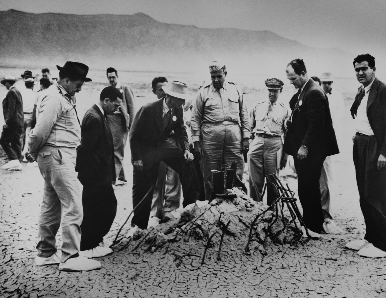 Groves and Oppenheimer examine twisted wreckage after the test blast. This is all that remained of a 100-foot tower, winch and shack that held the nuclear weapon.