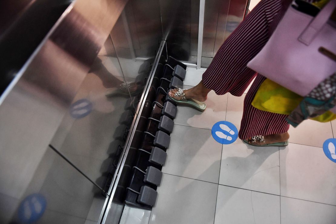 At a shopping mall in Bangkok, a woman uses a foot pedal to choose her floor.