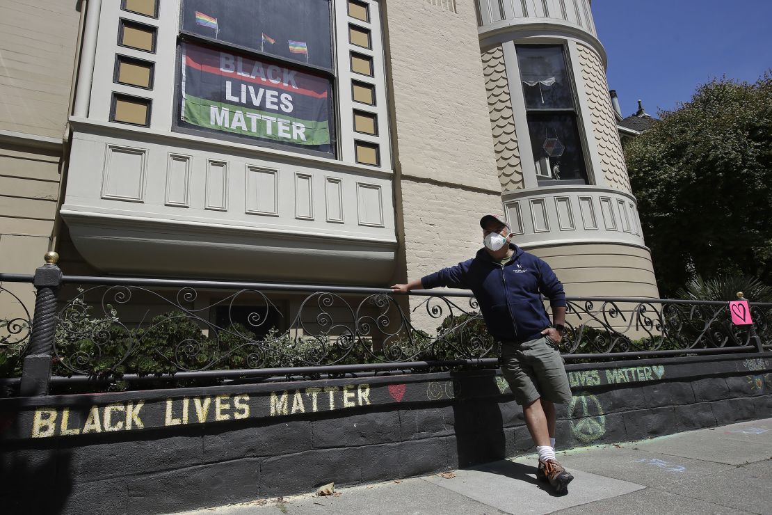 James Juanillo poses with a chalk message written outside of his home in San Francisco, California on June 14, 2020. 