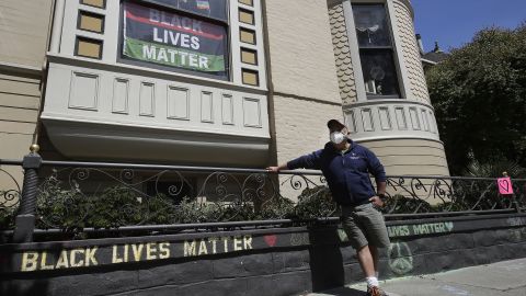James Juanillo poses with a chalk message written outside of his home in San Francisco, California on June 14, 2020.