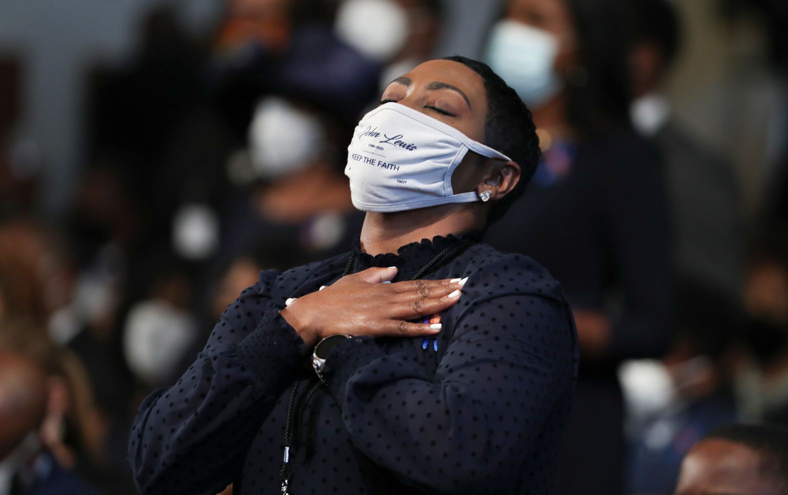 A woman becomes emotional during the funeral. Her face mask carries Lewis' name and the words "keep the faith."