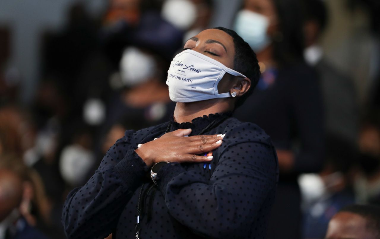 A woman becomes emotional during the funeral. Her face mask carries Lewis' name and the words "keep the faith."