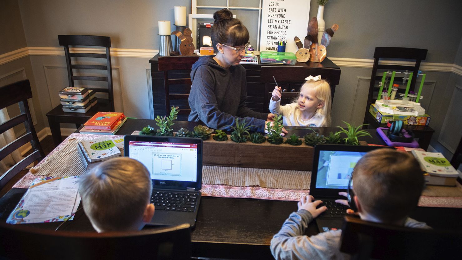 Austinville Elementary third grade teacher Emily Williams helps her daughter Lily, 3, as her two sons Braden, 10, bottom left, and Landen, 8, complete virtual school assignments in June at their home in Decatur, Alabama.