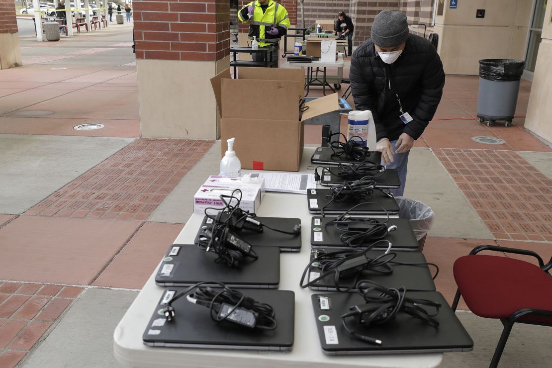 Minh Nguyen, a technology services worker with the Tacoma School District, cleans laptops to distribute to students in April.