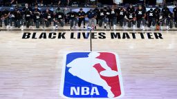 Members of the New Orleans Pelicans and Utah Jazz kneel together around the Black Lives Matter logo on the court during the national anthem before the start of an NBA basketball game Thursday, July 30, 2020, in Lake Buena Vista, Fla. (AP Photo/Ashley Landis, Pool)