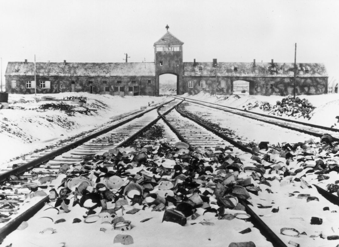 Snow-covered personal effects of those deported to the Auschwitz concentration camp litter the train tracks leading to the camp's entrance, in an image from around 1945. 