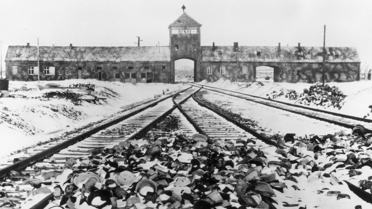 Snow-covered personal effects of those deported to the Auschwitz concentration camp litter the train tracks leading to the camp's entrance, in an image from around 1945. 