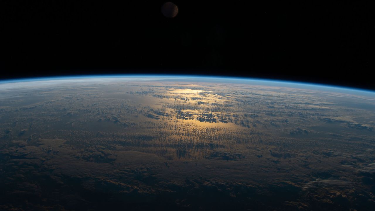 The sun's glint beams off a partly cloudy South Pacific as the International Space Station's orbital track took it halfway between Australia and South America on July 18, 2020.