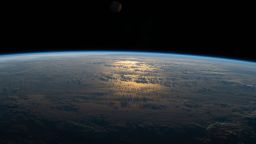 The sun's glint beams off a partly cloudy South Pacific as the International Space Station's orbital track took it halfway between Australia and South America on July 18, 2020.