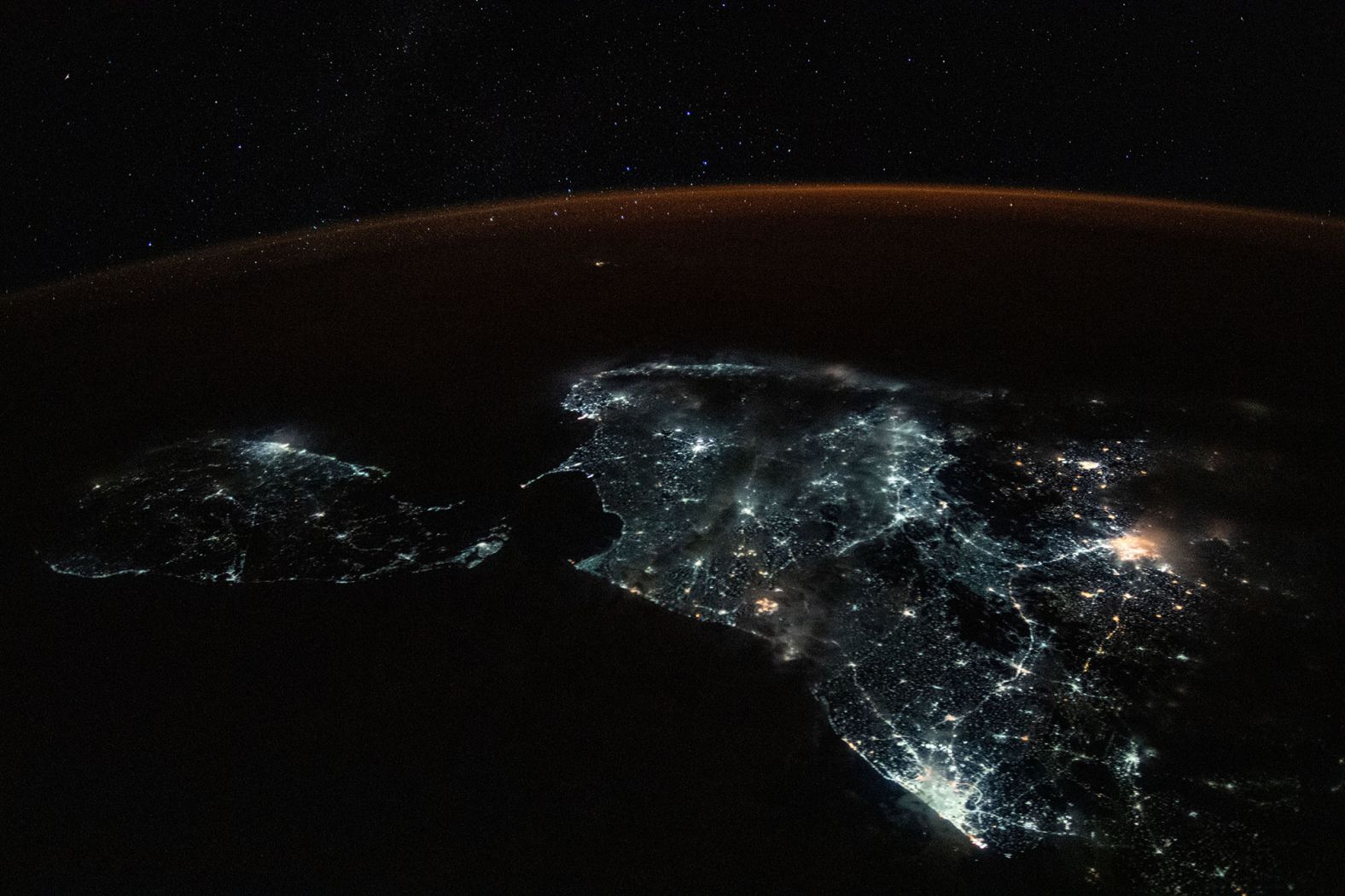 Sri Lanka and the brightly lit southern tip of India are shown in this photograph from the International Space Station on July 24. A starry sky and an atmospheric glow frame the Earth's horizon.