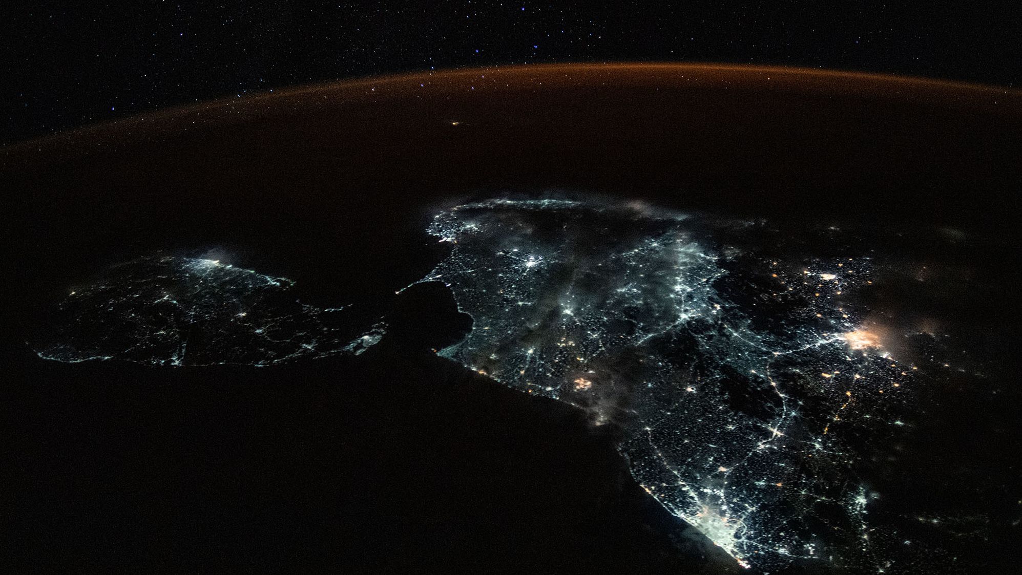 Sri Lanka and the brightly lit southern tip of India are shown in this photograph from the International Space Station on July 24. A starry sky and an atmospheric glow frame the Earth's horizon.