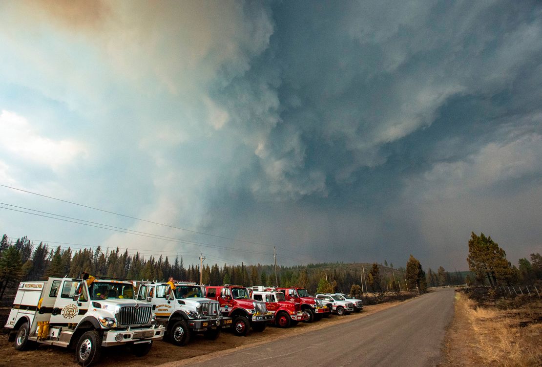 Firefighters look on as a smoke column collides with a thunderstorm cell near Susanville, California, July 21, 2020.