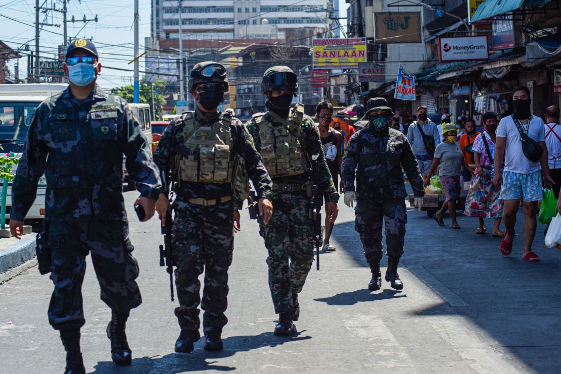 Elite policemen patrol a market while people shop during a government imposed enhanced quarantine as a preventive measure against the COVID-19 novel coronavirus in Manila on April 21.