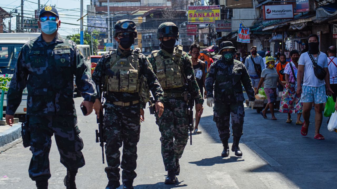 Elite policemen patrol a market while people shop during a government imposed enhanced quarantine as a preventive measure against the COVID-19 novel coronavirus in Manila on April 21.