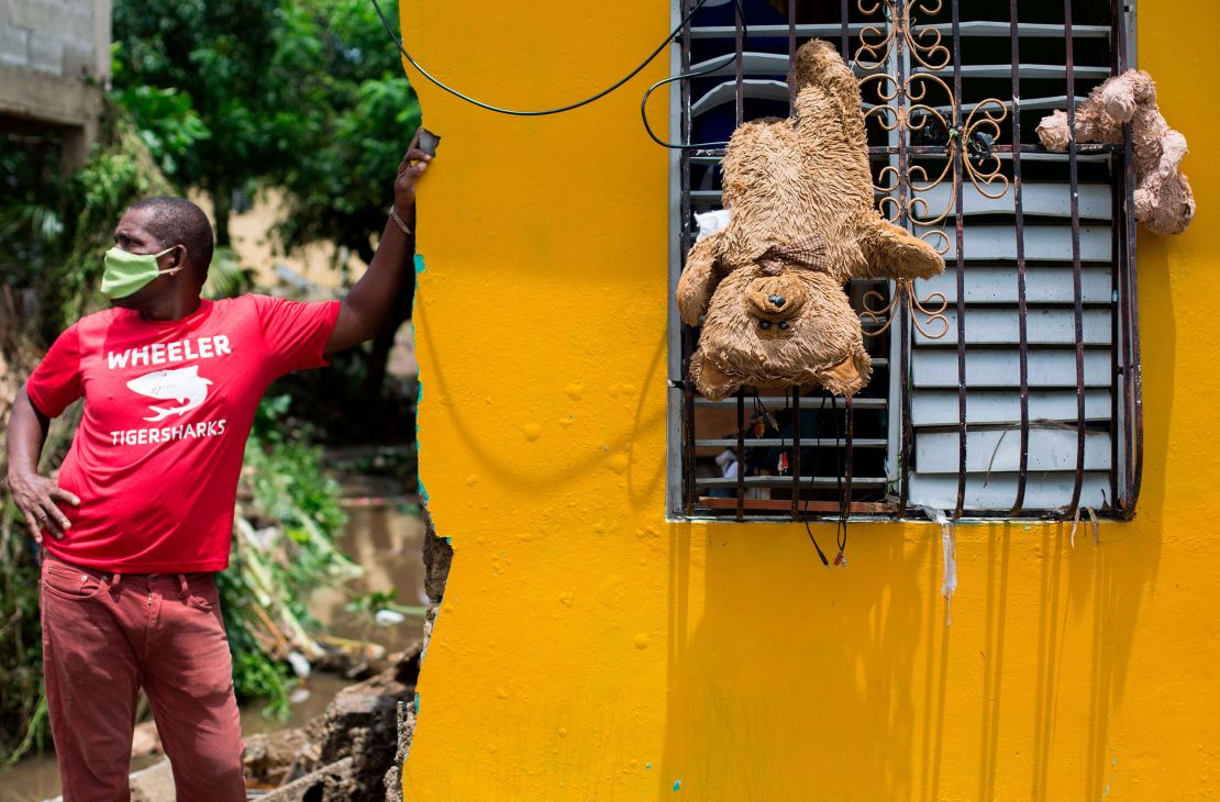 A man remains outside his home, where teddy bears hang from a window to dry after the passage of the storm throuth Hato Mayor, Dominican Republic, on July 31, 2020.