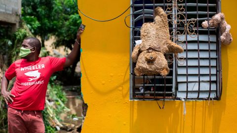 A man remains outside his home, where teddy bears hang from a window to dry after the passage of the storm throuth Hato Mayor, Dominican Republic, on July 31, 2020.