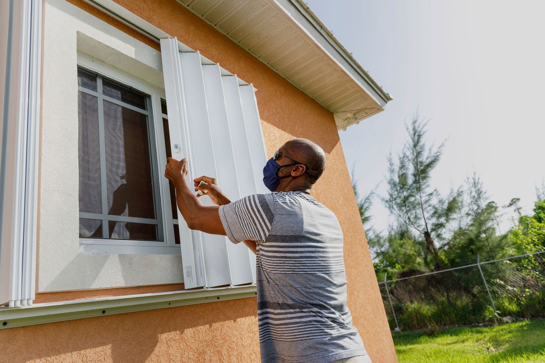 Wendell Smith unfolds storm shutters at his  home in Freeport in the Bahamas on Friday, July 31, 2020. 
