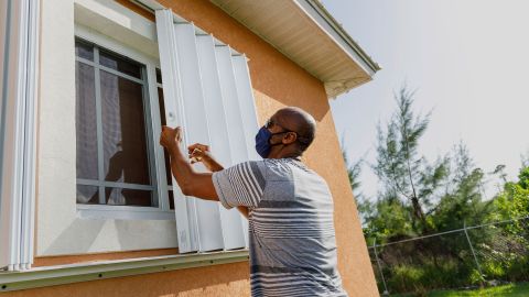 Wendell Smith unfolds storm shutters at his home in Freeport in the Bahamas on Friday, July 31, 2020.
