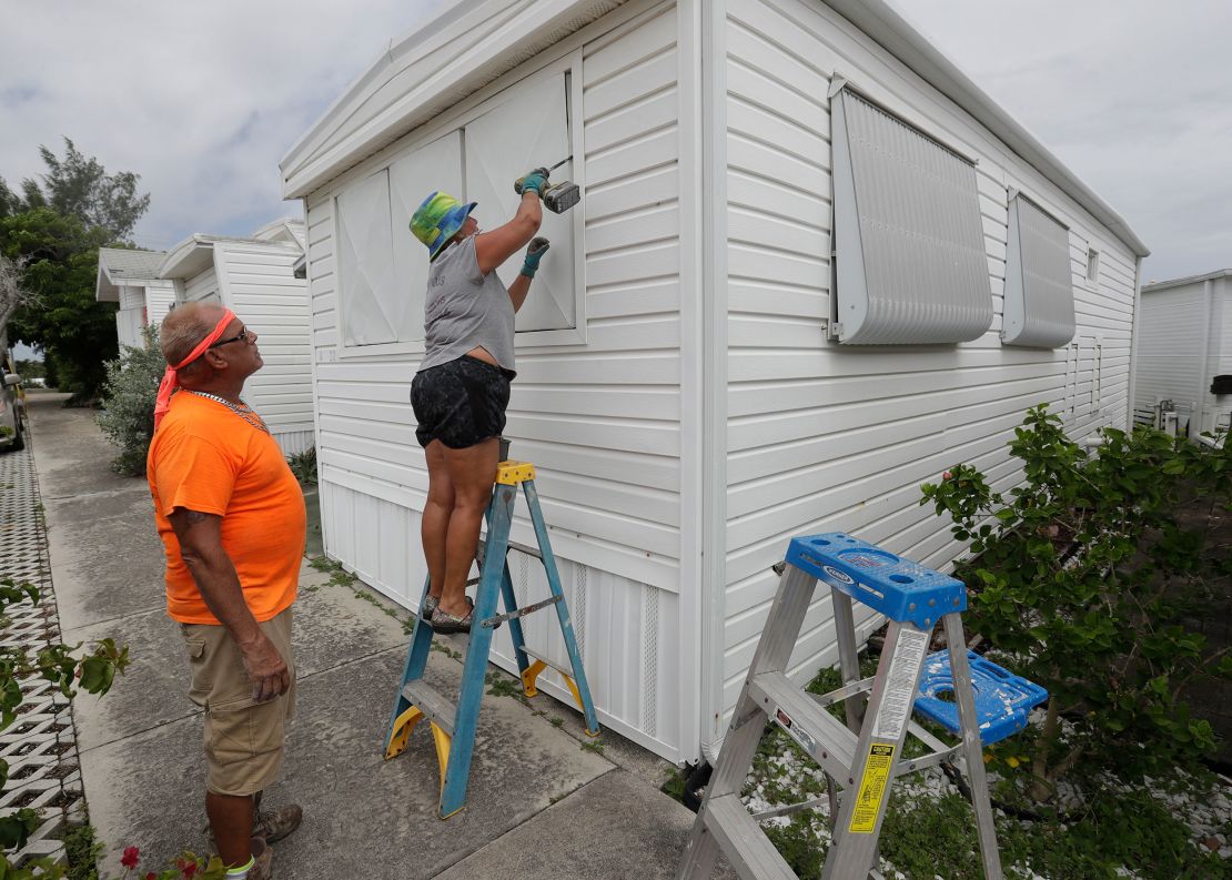 Chris Nagiewicz watches as his wife Mary attaches a hurricane panel on a trailer home in Briny Breezes, Florida, on Saturday, August 1. 