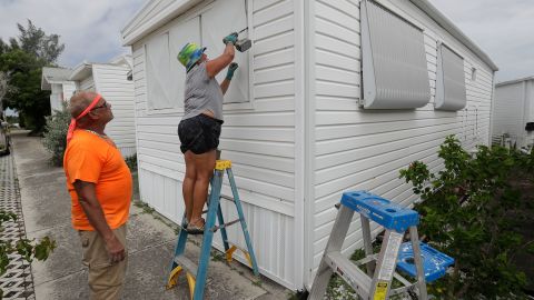 Chris Nagiewicz watches as his wife Mary attaches a hurricane panel on a trailer home in Briny Breezes, Florida, on Saturday, August 1.
