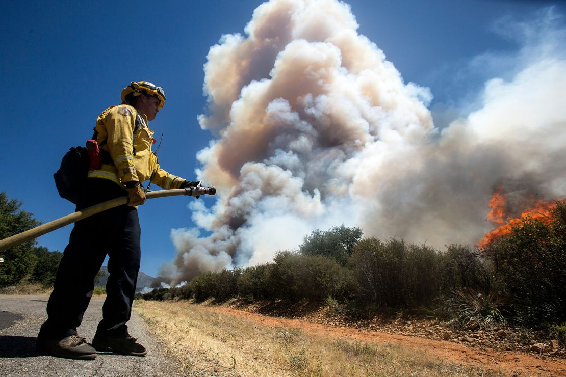A firefighter readies a hose at the Apple Fire in Cherry Valley, Calif., Saturday, Aug. 1, 2020.