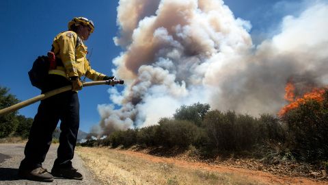A firefighter readies a hose at the Apple Fire in Cherry Valley, Calif., Saturday, Aug. 1, 2020.