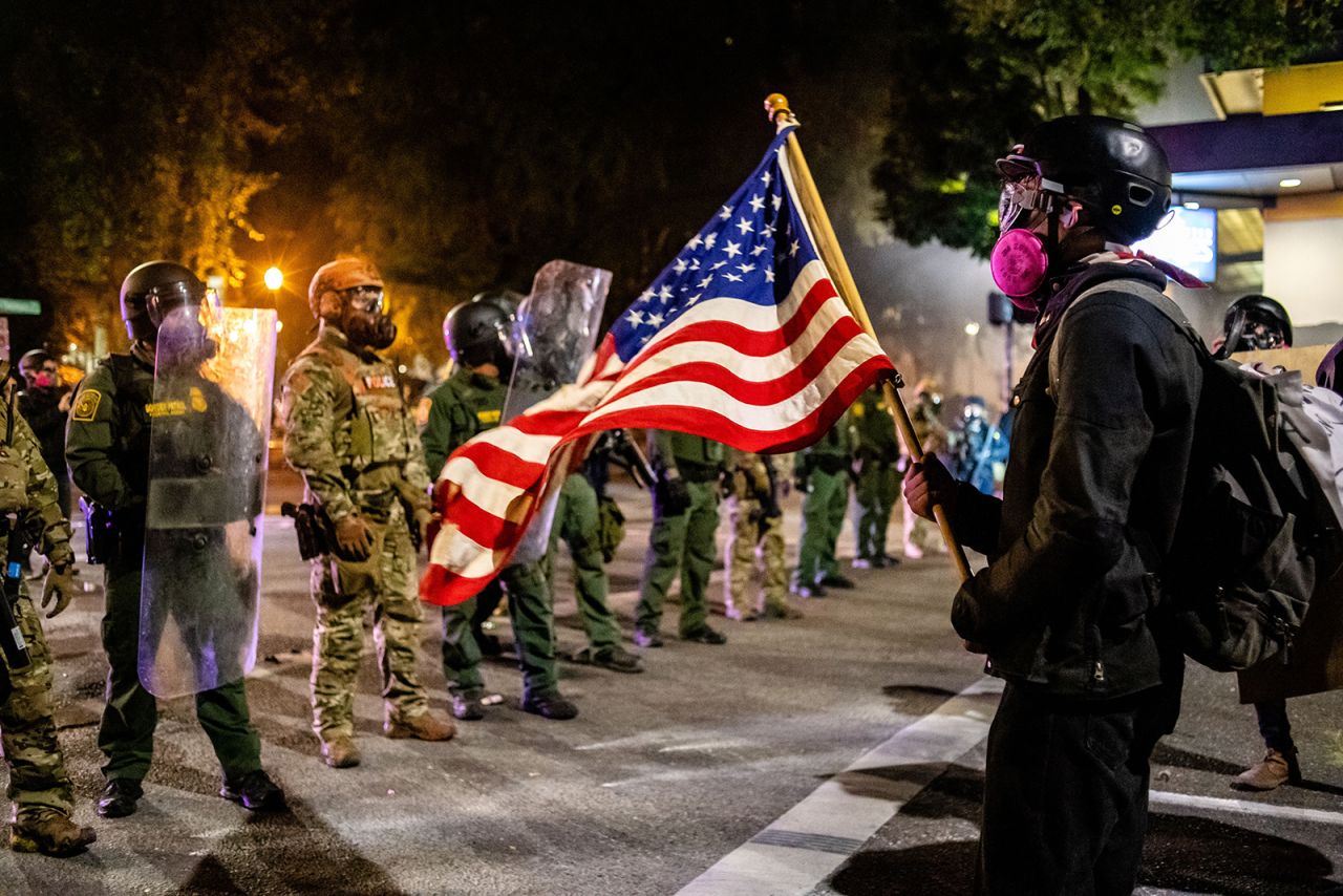 A protester holds up an American flag in front of federal officers on July 30.