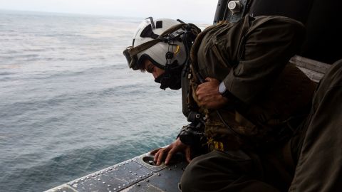 Naval Air Crewman 2nd Class Joseph Rivera, a search and rescue swimmer looking out of a US Navy MH-60 Seahawk, helped conduct the search and rescue relief operations.
