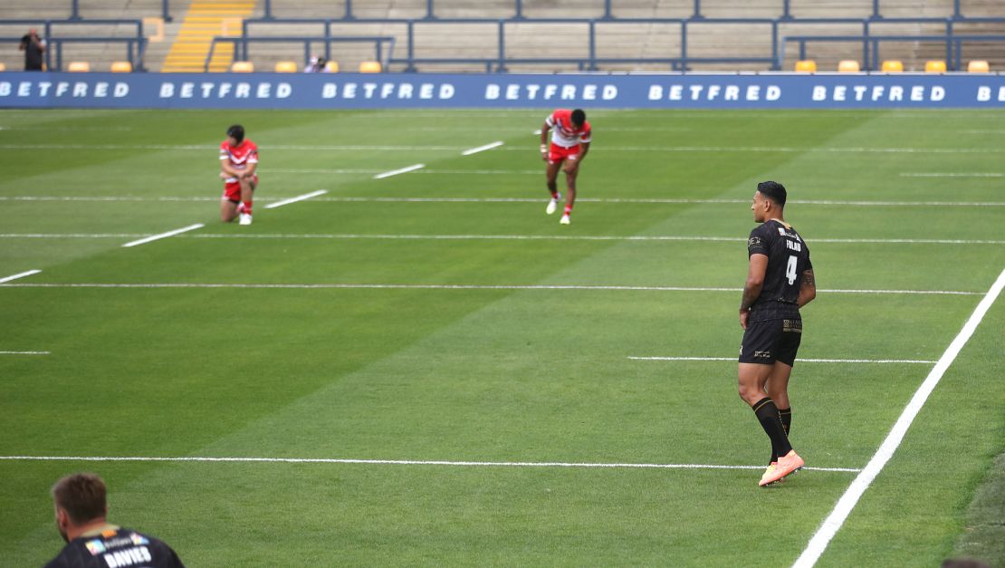 Catalans Dragons' Israel Folau remains standing as players kneel in support of the Black Lives Matter movement. 