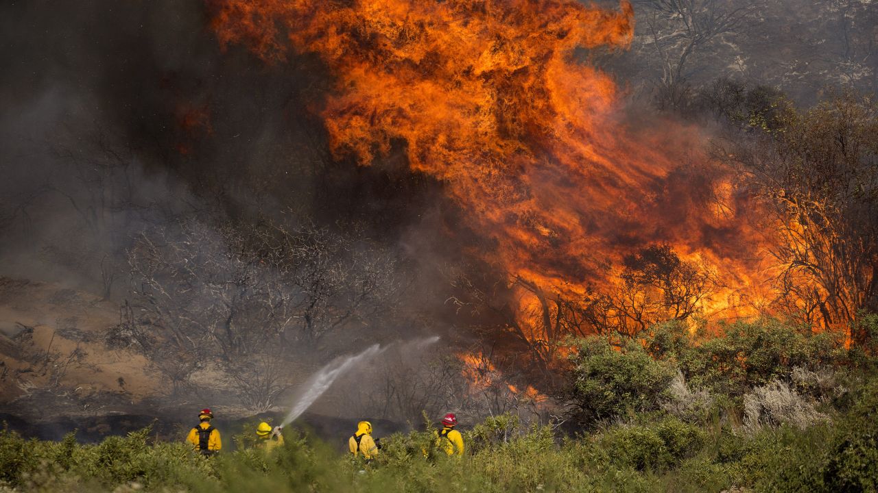 Firefighters work against the Apple Fire near Banning, California, on Sunday