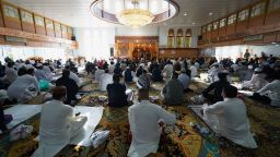 People sit while social distancing inside Manchester Central Mosque, in Manchester, northern England, after having their temperatures checked on July 31.