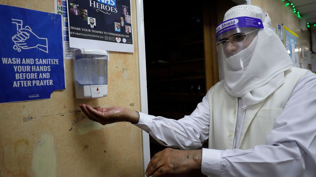 A volunteer uses hand sanitizer as he enters Minhaj-ul-Quran Mosque in London on July 31.