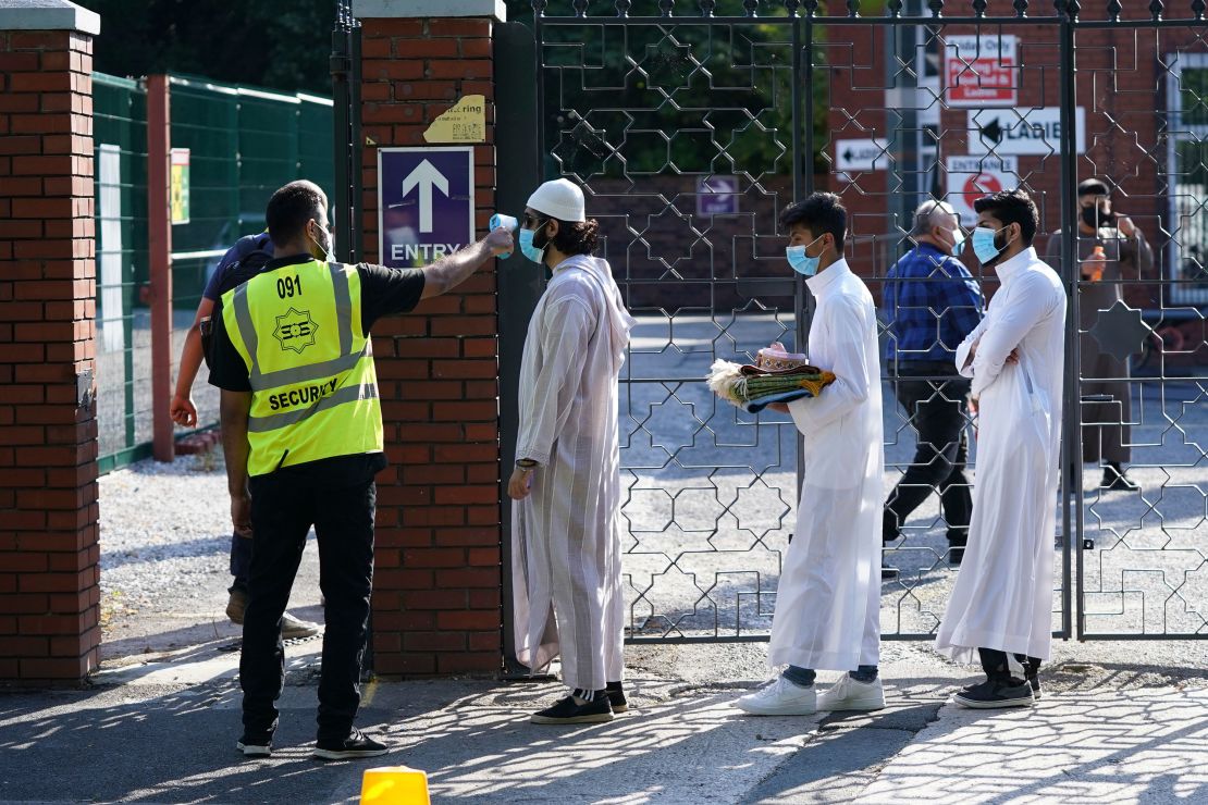 People wearing face masks have their temperatures checked before being allowed to go into Manchester Central Mosque on July 31.