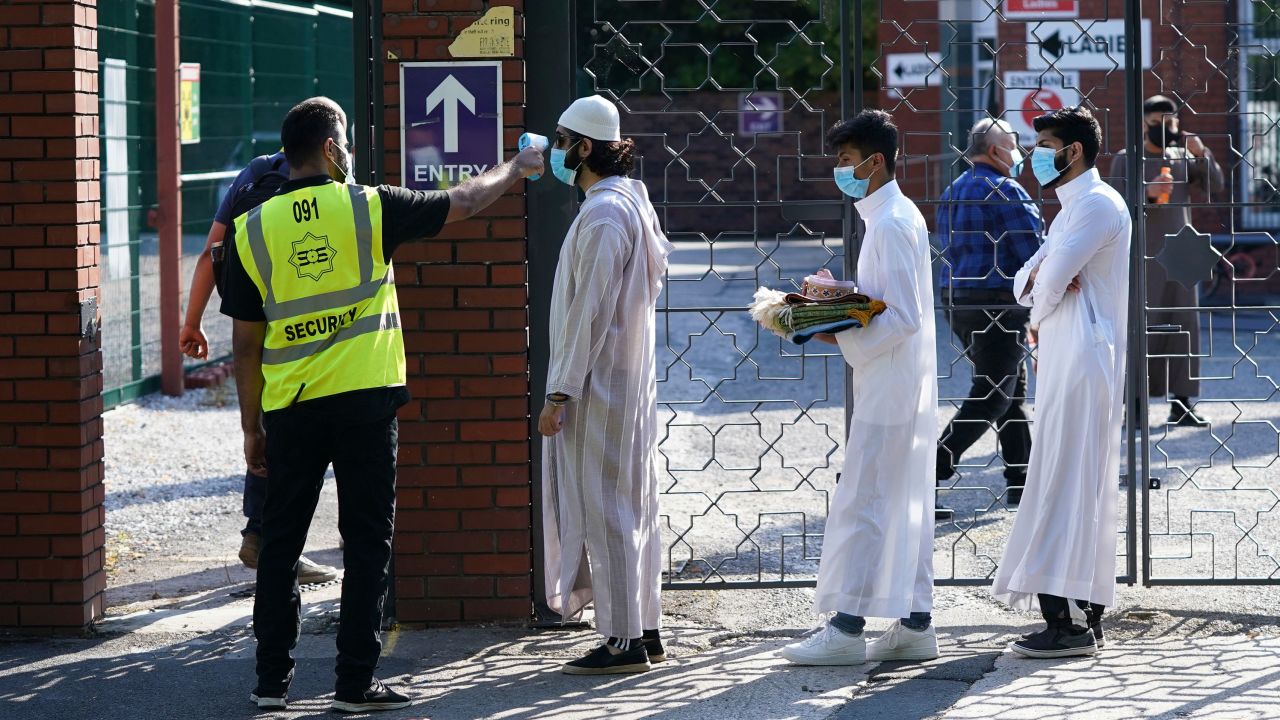 People wearing face masks have their temperatures checked before being allowed to go into Manchester Central Mosque on July 31.