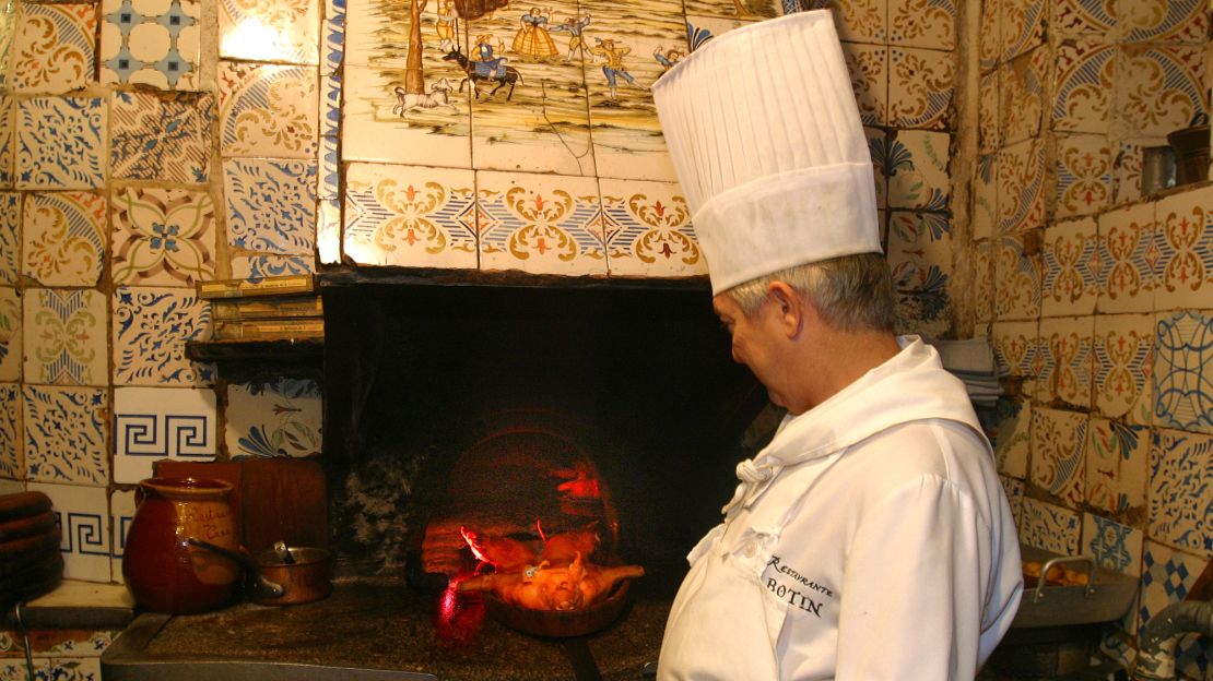 An employee at Restaurante Botín pulls a roasted pig out of the oven.